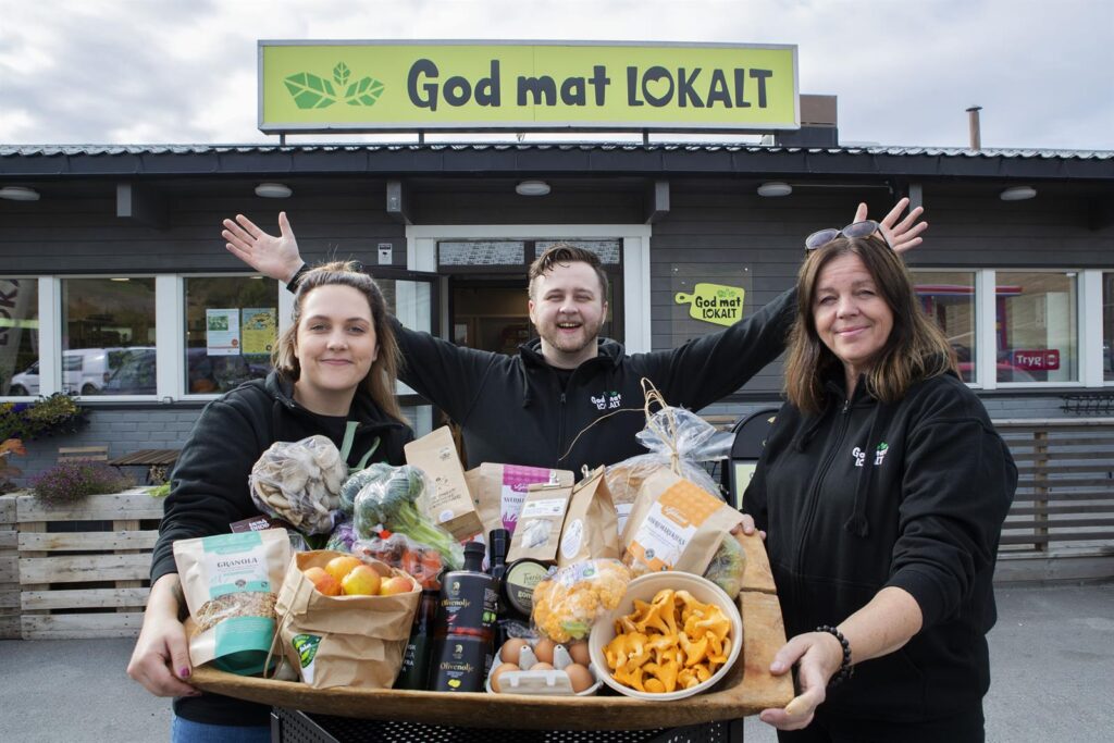 Tre ansatte i God Mat Lokalt med et brett bugnende av lokalmat